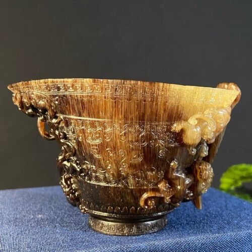 TS-JL00-001-horn-relief-cup Carved natural horn relief cup with dragon-head finial on the rim, displayed on blue cloth